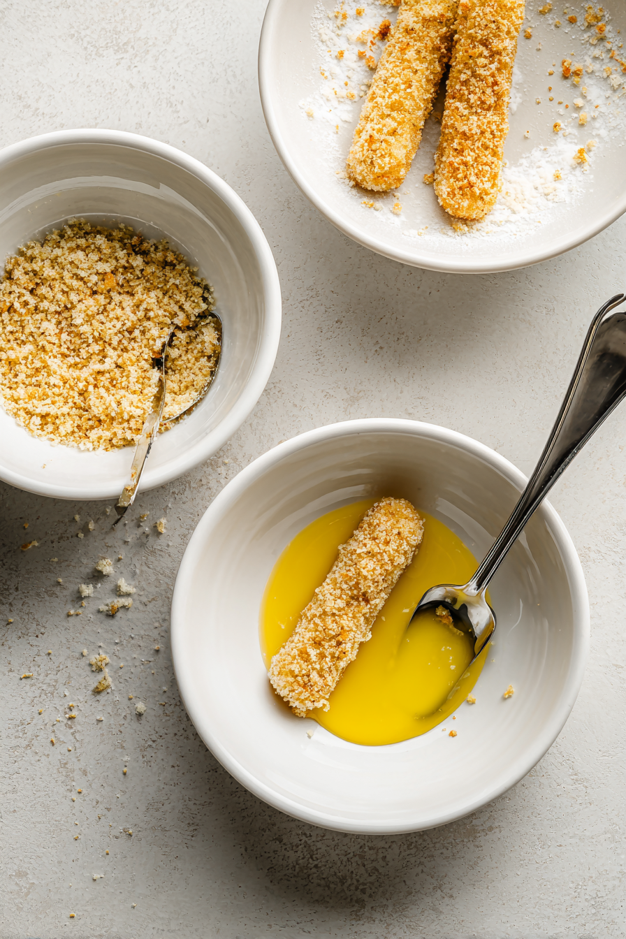 Dip each cheese stick in egg, then coat with bread crumbs. Repeat for all sticks.