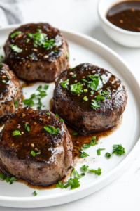 This image shows the finished filet mignon steak topped with a savory marsala wine sauce and sautéed mushrooms, beautifully plated and ready to be served.