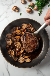 This image shows dry marsala wine and beef stock being poured into the pan with mushrooms, shallots, and garlic, simmering to form a rich and flavorful marsala sauce.