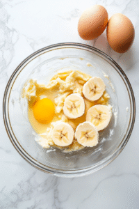 Mash up some bananas with a fork until they look like chunky applesauce. Toss them into the butter-sugar mix. Mash up some bananas with a fork until they look like chunky applesauce. Toss them into the butter-sugar mix.