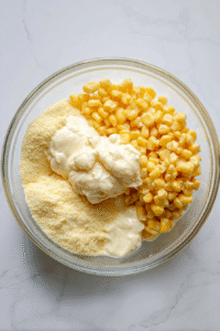 In a mixing bowl, combine butter, whole corn, creamed corn, cornbread mix, and sour cream.
