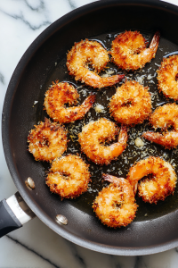 Heat coconut oil in a large skillet over medium heat. Cook shrimp for 2 minutes on each side until golden and curled.