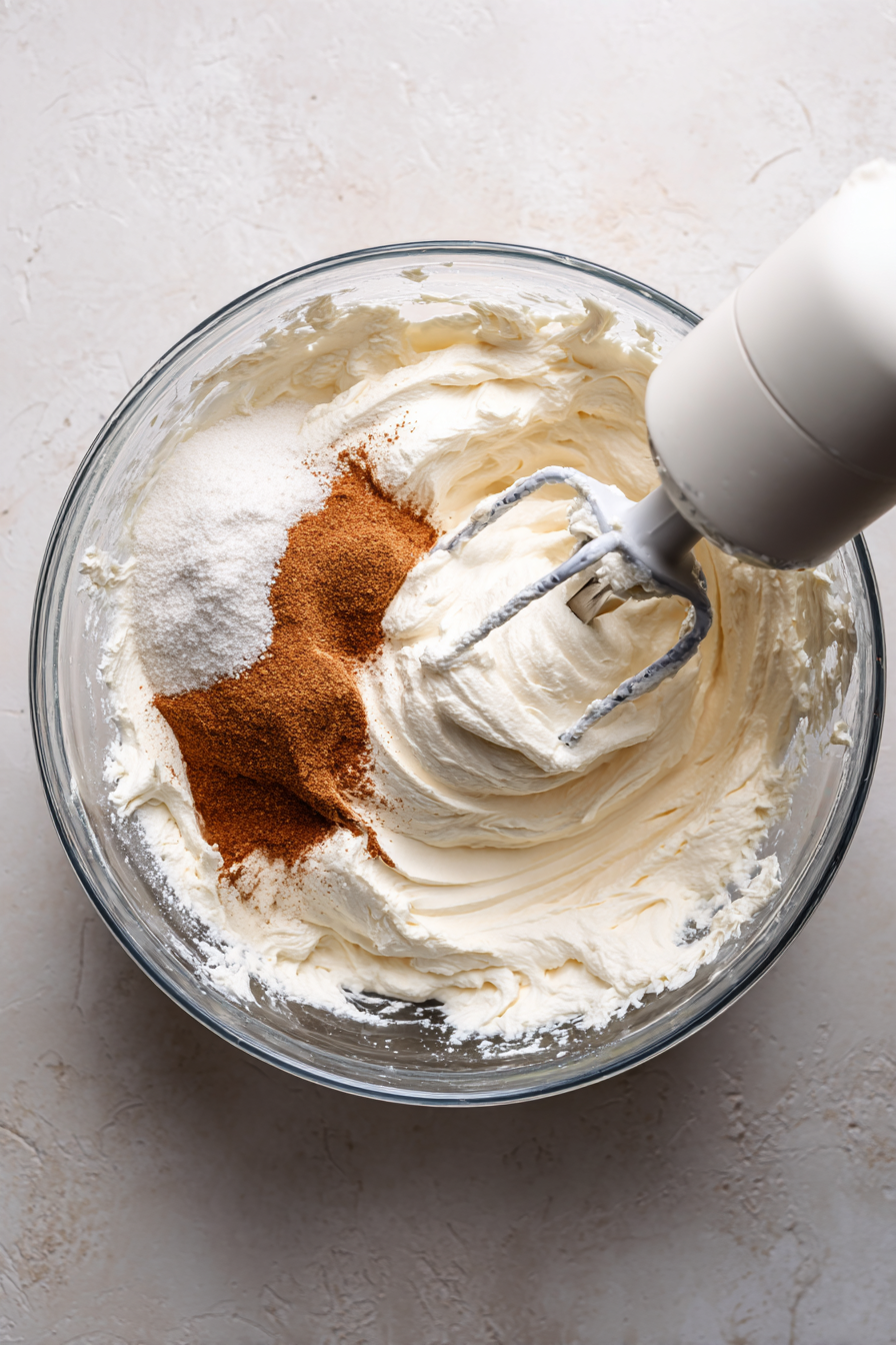 Beat cream cheese, sugar, flour, sour cream, vanilla, and cinnamon. Add eggs.