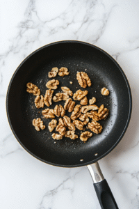 Throw some walnuts into a skillet on low heat. Keep stirring so they don't burn. Once they're lightly roasted, chop them up coarsely and let them cool to room temperature.