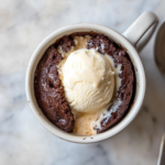 the image shows the brownie in a mug with ice cream over the top.