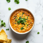 A vibrant pot filled with a creamy, smooth Velveeta cheese sauce made with Rotel tomatoes and green chilies, garnished with fresh cilantro. This delicious cheese sauce is ready to serve as a dip or topping for your favorite snacks.