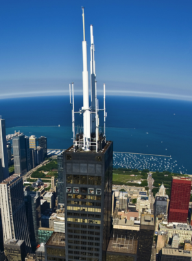 A thrilling view of visitors experiencing the glass ledge at Skydeck Chicago, overlooking the city from the iconic Willis Tower. The image captures the excitement and awe of standing over the edge, with the vast cityscape visible below. This experience highlights Chicago’s adventurous side and offers a unique perspective of the skyline.