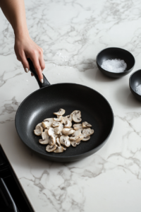 Cooking sliced mushrooms in a pan for Grilled Cheese with Mushrooms, Garlic, Chili, and Oregano