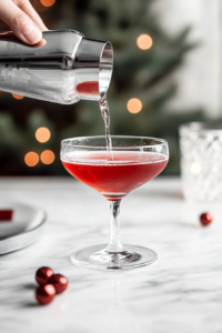 Straining the Spiced Cognac Cocktail into a Sugar-Rimmed Coupe Glass
