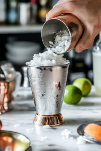 adding coconut milk and rum to mint mixture for coconut mint rum cocktail