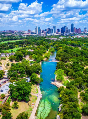 arton Springs Pool with people swimming: A view of Barton Springs Pool, a natural spring-fed pool in Zilker Park. People can be seen swimming and relaxing in the clear blue water, surrounded by lush greenery, making it a popular spot in the city.