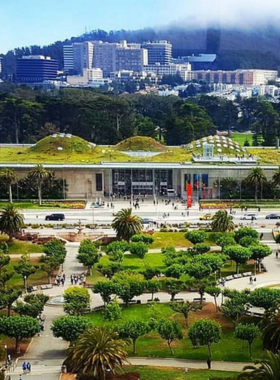 California_Academy_of_Sciences_Exterior.jpg A striking exterior view of the California Academy of Sciences, showcasing its unique architecture with a green living roof adorned with native plants. The building features large glass panels that reflect the surrounding landscape, allowing natural light to flood the interior. Visitors can be seen entering the museum, highlighting its role as a popular destination for learning about science and nature in Golden Gate Park, San Francisco.