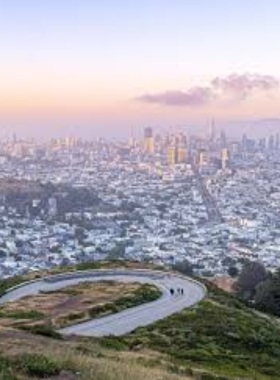San_Francisco_Cityscape_Sunset.jpg A stunning sunset view of the San Francisco cityscape, showcasing a skyline filled with modern skyscrapers silhouetted against a vibrant sky painted with shades of orange, pink, and purple. The golden rays of the setting sun reflect off the glass buildings, creating a warm glow over the bustling city below. This captivating scene captures the essence of San Francisco as a lively urban center that transitions beautifully from day to night.