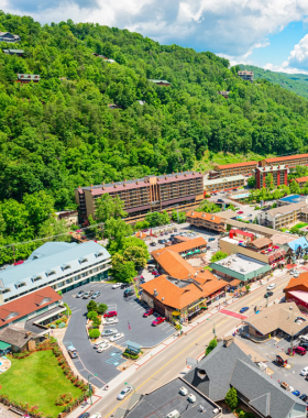 Downtown Gatlinburg A vibrant view of downtown Gatlinburg showcasing bustling streets lined with charming shops and restaurants. The scene is set against a backdrop of lush green mountains, capturing the lively atmosphere of this popular tourist destination.