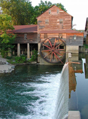 Old_Mill_Pigeon_Forge The historic Old Mill in Pigeon Forge, featuring a picturesque waterwheel and rustic mill structure. The mill is surrounded by trees, creating a tranquil, nostalgic atmosphere.