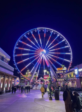Great_Smoky_Mountain_Wheel The Great Smoky Mountain Wheel at Pigeon Forge, a towering Ferris wheel with gondolas, set against a scenic mountain background. The illuminated wheel adds a lively touch to the evening sky.