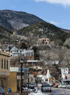 manitou-springs-mineral-spring.jpg This image shows a natural mineral spring in Manitou Springs, with people filling their bottles from the bubbling waters surrounded by lush greenery.