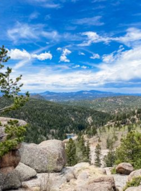 mueller-state-park-hiking-trail.jpg This image shows a scenic hiking trail at Mueller State Park, surrounded by trees and rolling hills, with bright sunshine filtering through the leaves.