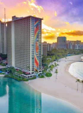 Waikiki Beach Sunset This image shows the stunning sunset over Waikiki Beach, with golden hues reflecting on the calm water, palm trees swaying gently in the breeze, and visitors enjoying the peaceful atmosphere on the sandy shore.
