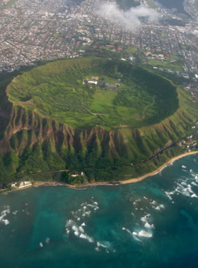 Diamond Head Hike Trail This image shows hikers climbing the famous Diamond Head Trail, surrounded by lush greenery and rocky terrain. The steep ascent leads to a panoramic view of Waikiki and the Pacific Ocean at the summit.
