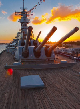 Battleship Missouri Memorial Tour This image shows the Battleship Missouri Memorial, with visitors exploring the ship’s decks and admiring its historical significance. The ship is docked at Pearl Harbor, where Japan formally surrendered during World War II.