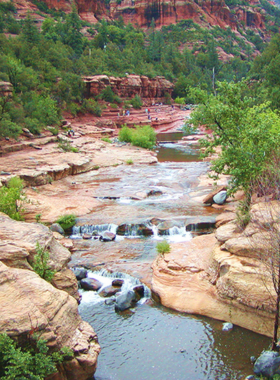 Slide-Rock-State-Park-Sedona This image shows the fun-filled Slide Rock State Park, Sedona, with visitors sliding down natural water slides formed by Oak Creek and surrounded by stunning red rock scenery.