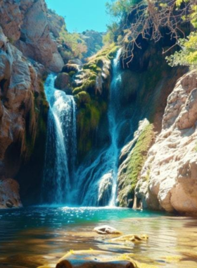 Tahquitz Canyon This image shows the stunning waterfall in Tahquitz Canyon, surrounded by rocky cliffs and desert plants, with hikers exploring the scenic path leading to this natural beauty.