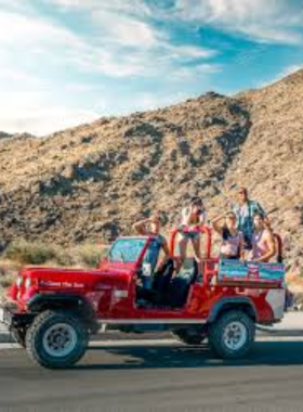 Desert Adventures Red Jeep Tours This image shows a red jeep on a thrilling desert tour through rocky terrain, with a guide sharing insights about the Coachella Valley’s unique desert landscapes and history.