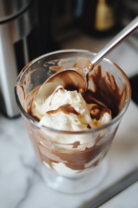 stirring hot chocolate cocktail mixture in clear glass with metal spoon