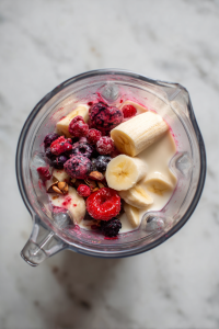 Add frozen berries, banana slices, and 2–3 tbsp almond milk to a blender.