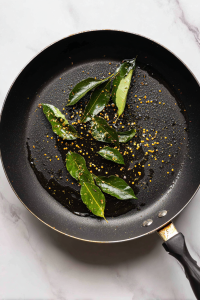 In the same pan, heat another tbsp oil. Add mustard seeds, cumin seeds, and curry leaves.