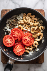 Add tomatoes and cashews, cook until soft, then blend into a smooth paste.