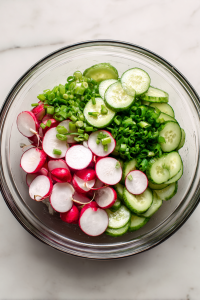 In a mixing bowl, combine cucumber, radish, and chives.