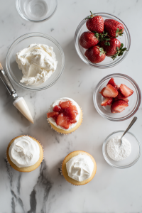 Mix chopped strawberries and jam for the filling. Core the cooled cupcakes, fill with strawberry mixture, and top with whipped cream.