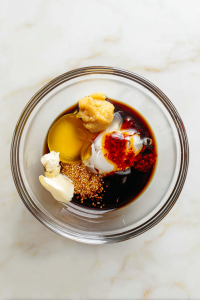 In a bowl, mix sesame oil, soy sauce, rice vinegar, ginger paste, garlic, honey, and chili oil.