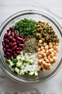 In a large bowl, combine beans, onion, cucumber, capers, parsley, and oregano.
