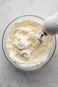 Beat cream cheese until smooth. Add sugar, salt, sour cream, lemon zest, and vanilla. Mix until combined.