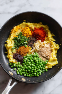 Boil and mash potatoes; sauté spices, peas, and mashed potatoes in a pan.