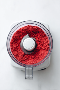 Pulse freeze-dried strawberries into a fine powder using a grinder.