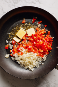 In a skillet, sauté onions, red bell pepper, and garlic in butter.