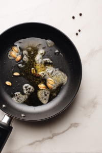 Heat oil and butter in a pan, then sauté cloves, cardamom, onion, garlic, and ginger.