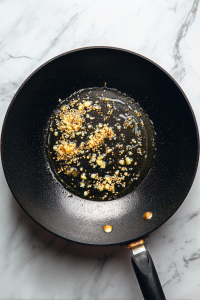 Heat oil and ghee in a kadai. Add cumin, chopped garlic, and ginger. Sauté till aromatic.