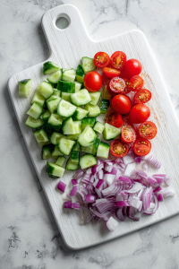 Wash and finely chop cucumbers, tomatoes, and onions.